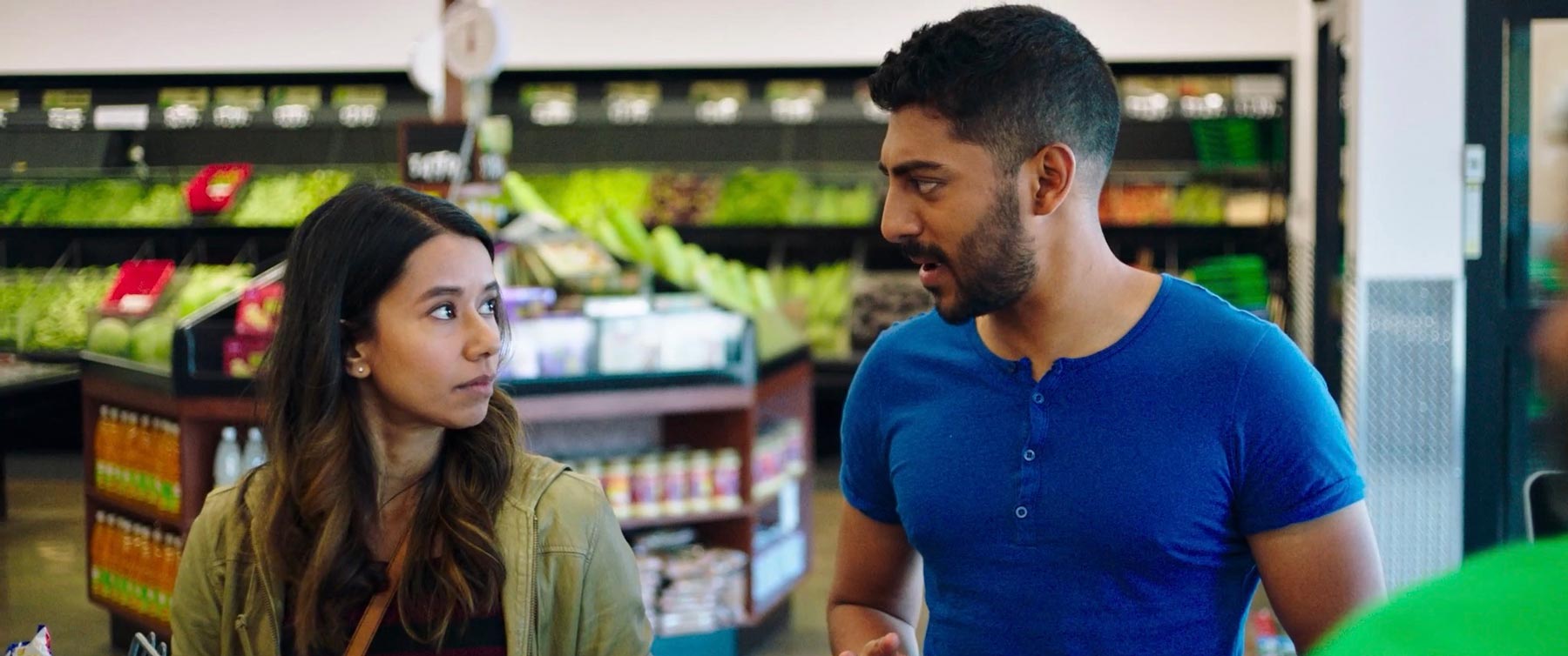 Definition Please film still: Young woman and man looking at each other as they speak in a grocery store